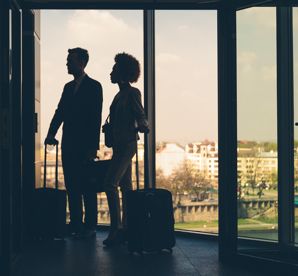 Silhouette of woman and man holding suitcases standing in hotel hall and waiting for elevator.