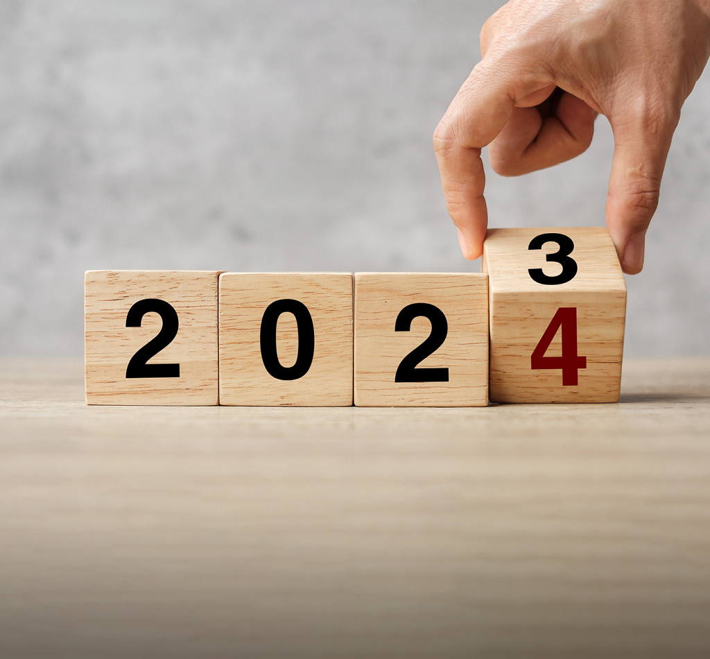 Hand flipping wooden blocks from 2023 to 2024, text on table.